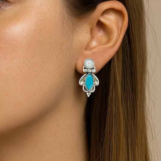 Close-up of a woman wearing a silver earring with a turquoise stone.