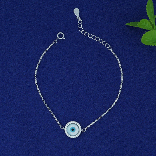 Silver bracelet with a blue eye charm on a blue background