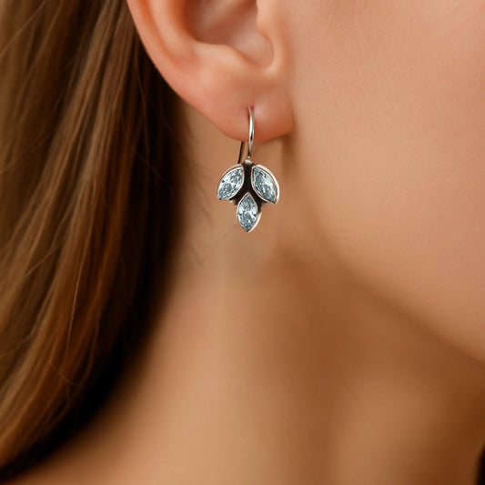 Close-up of a woman wearing a silver drop earring with gemstones.
