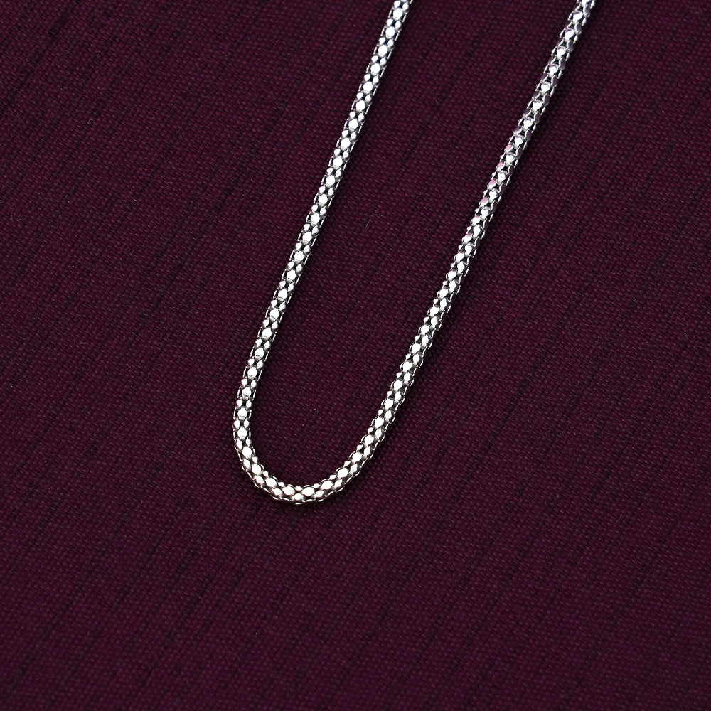 Silver crub chain necklace on a dark purple fabric background