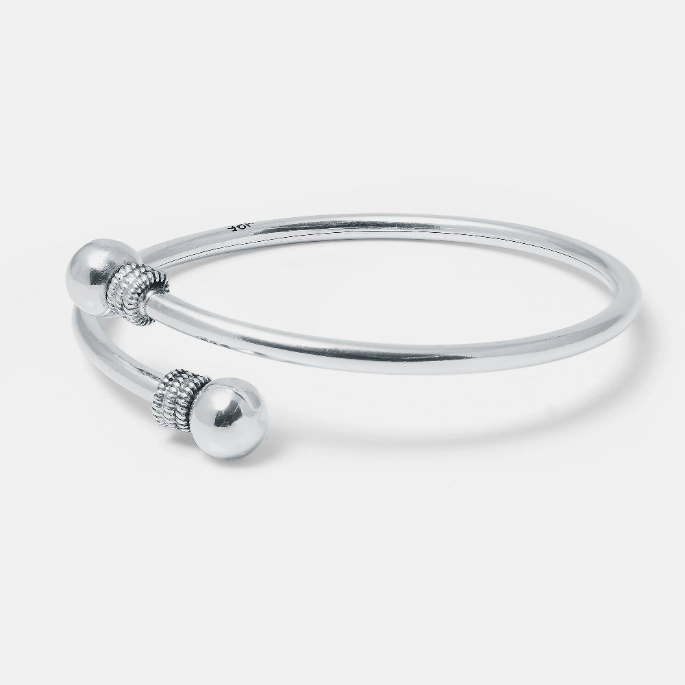 Silver bangle with decorative elements on a light gray background