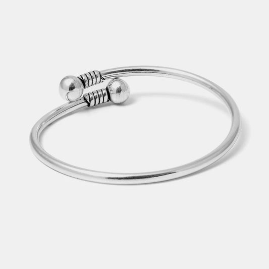 Silver bracelet with two spherical ends on a light gray background