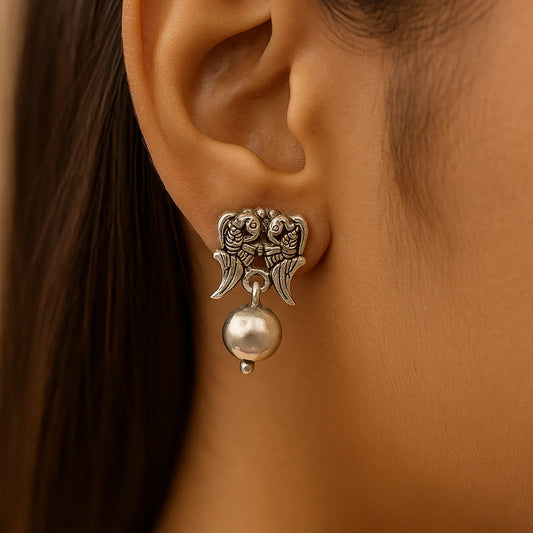 Silver earring with a ball detail worn by a person