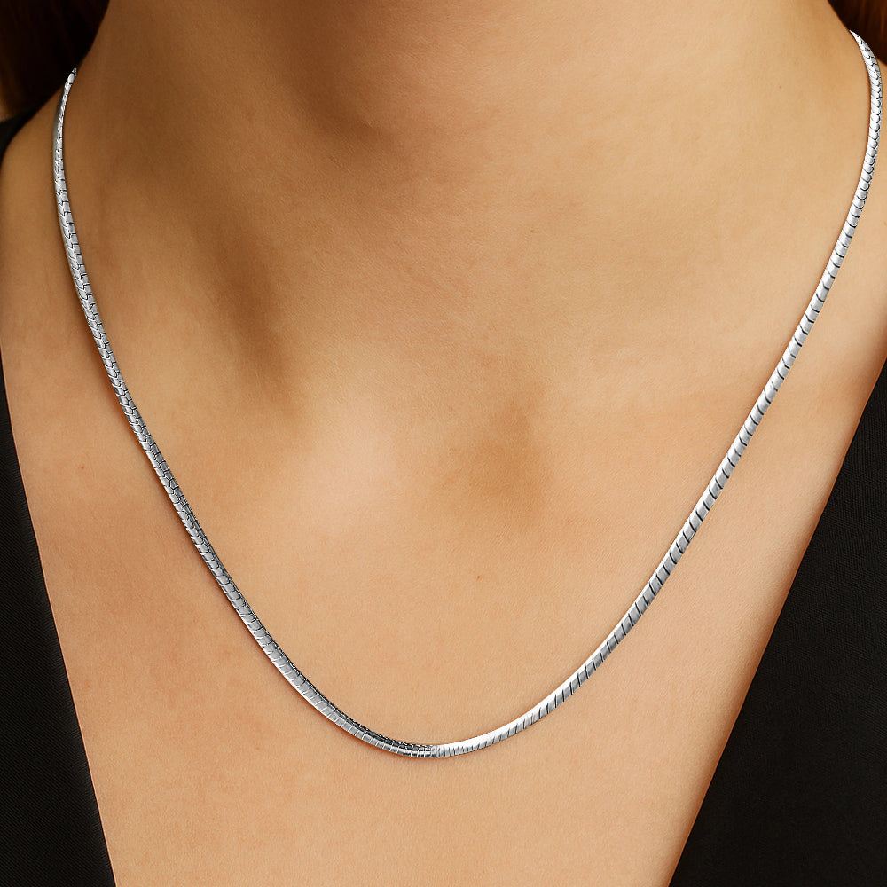 Silver necklace on a person's neck against a black background
