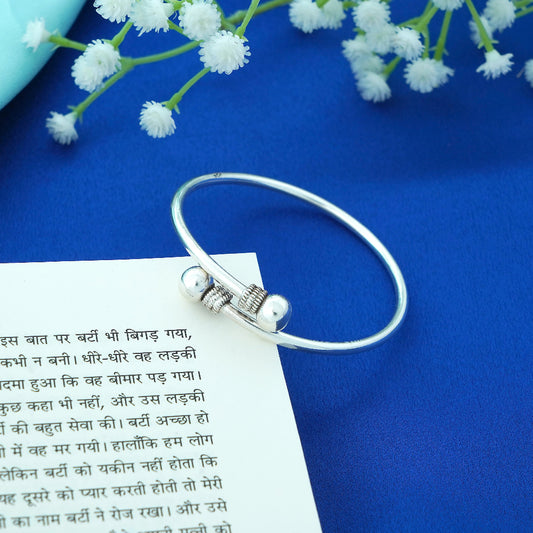 Silver bracelet on a piece of paper with text, against a blue background with white flowers.