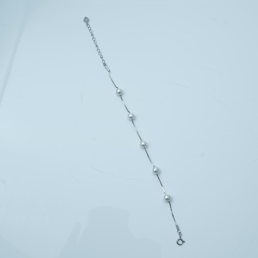 Silver bracelet with small beads on a light gray background