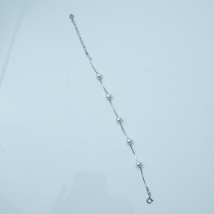 Silver bracelet with small beads on a light gray background