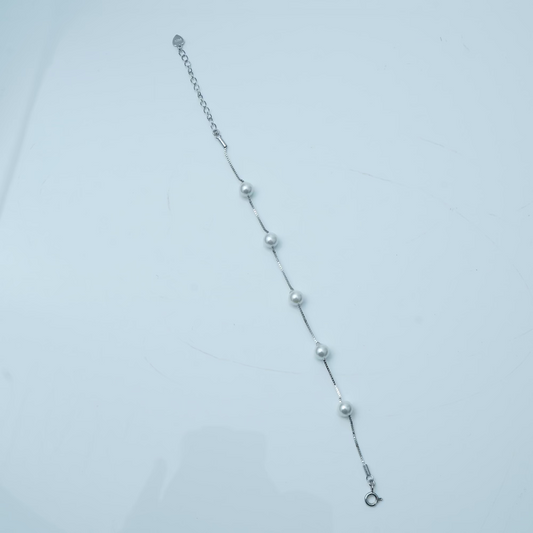 Silver bracelet with small beads on a light gray background
