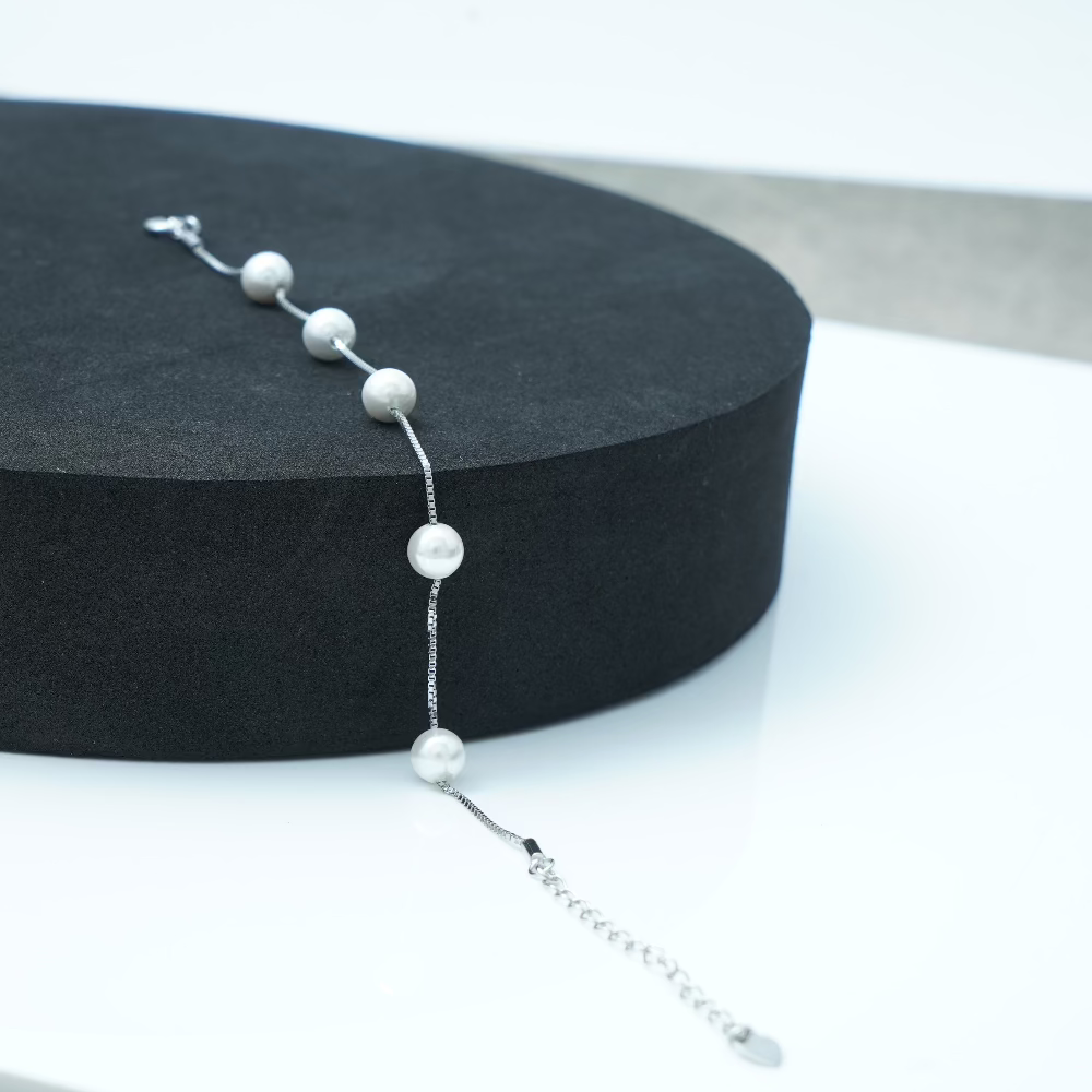 Pearl bracelet on a black stand with a white background