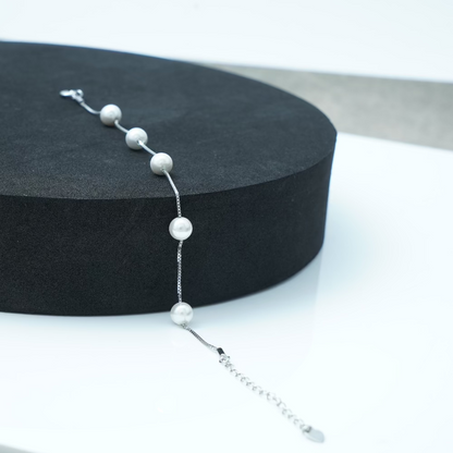 Pearl bracelet on a black stand with a white background