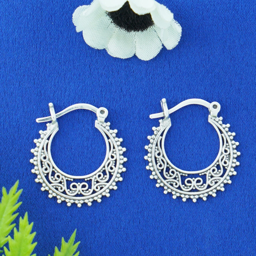 Silver hoop earrings on a blue background with decorative elements.