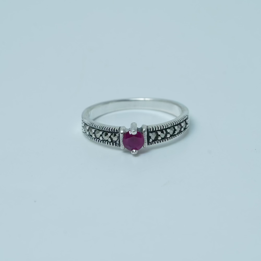 Silver ring with a heart-shaped purple gemstone on a light gray background