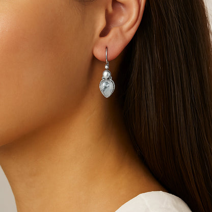 Close-up of a woman wearing a silver earring with a clear gemstone.