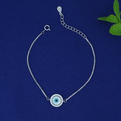 Silver bracelet with a blue eye charm on a blue background