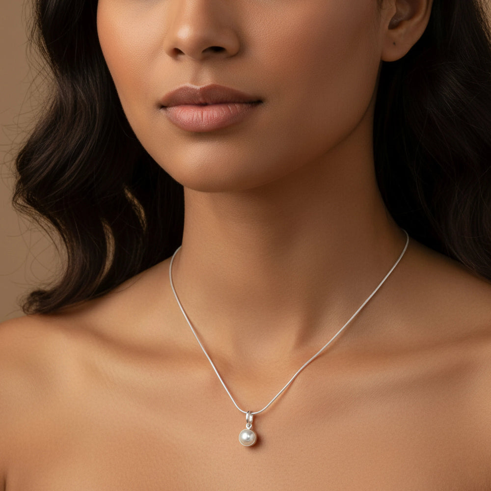 Close-up of a woman wearing a silver necklace with a pearl pendant by Silver World.