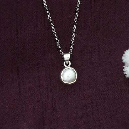 Silver necklace with a pear lpendant on a dark purple fabric background