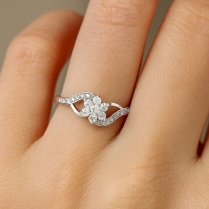Silver ring with floral design on a finger against a neutral background