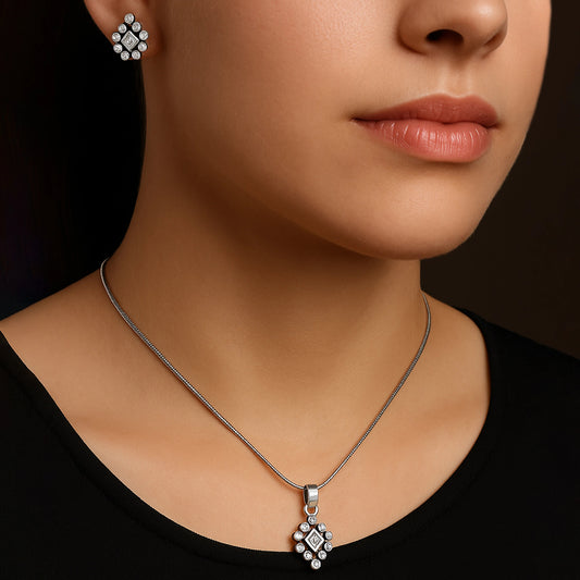 Close-up of a woman wearing a silver necklace with a pendant and matching earrings.