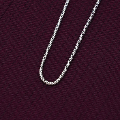 Silver crub chain necklace on a dark purple fabric background