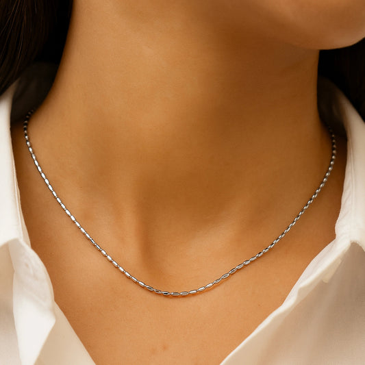 Silver necklace on a person wearing a white shirt