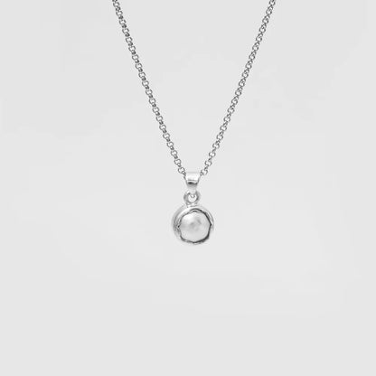 Silver necklace with a round pendant on a light gray background