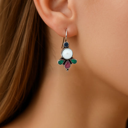 Close-up of a woman wearing a decorative silver stone earring with a white center and colored accents.