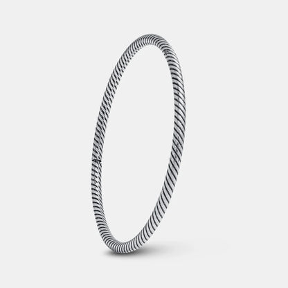 Silver bangle with a striped pattern on a light gray background