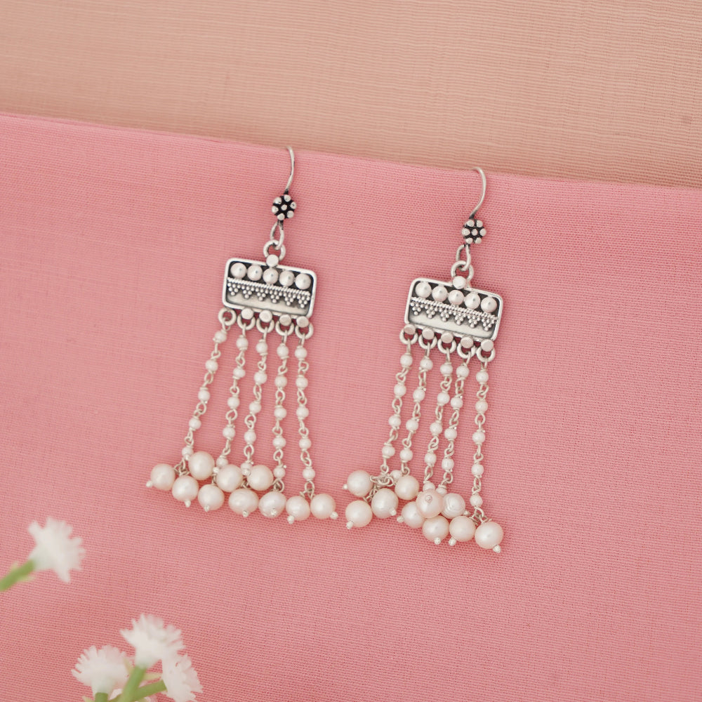 Pearl hanging earrings with silver fringe on a pink background