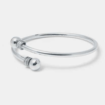 Silver bangle with decorative elements on a light gray background