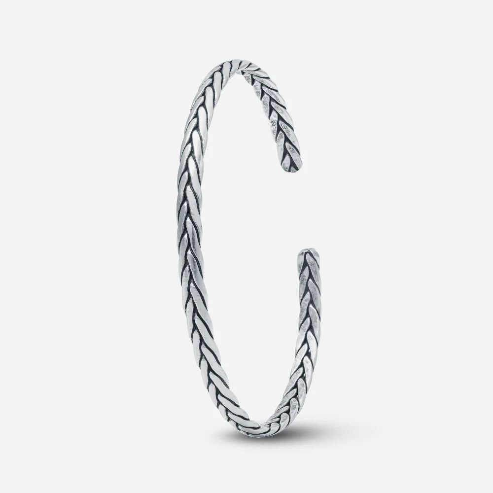 Silver bangle with braided design on a white background