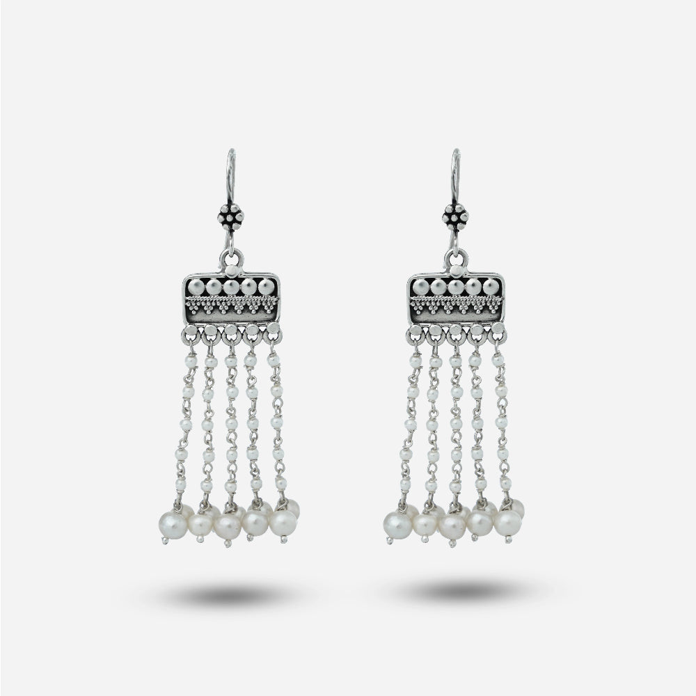 Pair of silver hanging earrings with pearl drops on a white background
