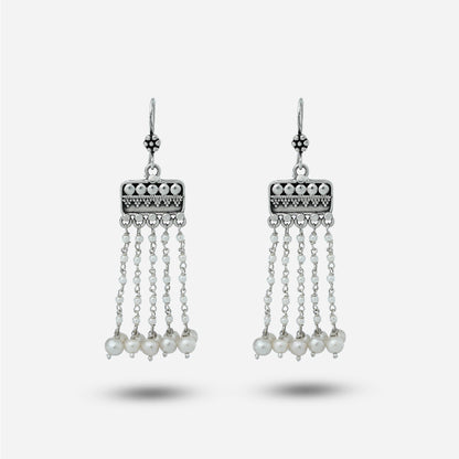 Pair of silver hanging earrings with pearl drops on a white background