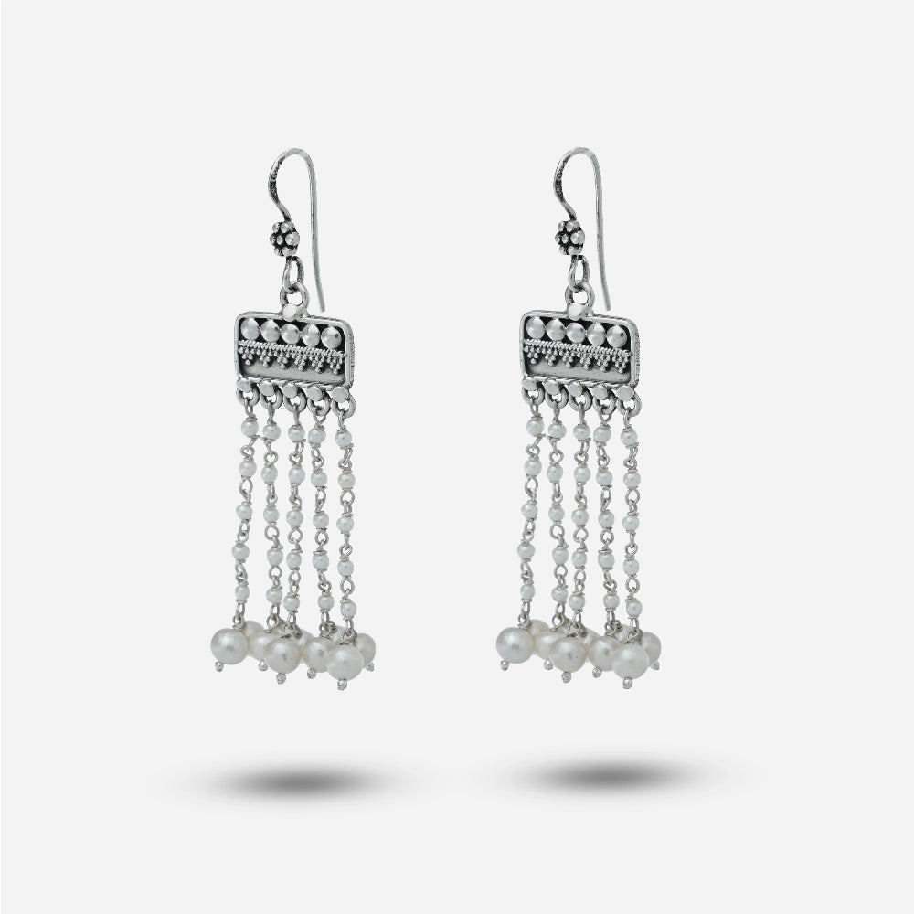 Silver chandelier earrings with pearl-like beads on a light gray background