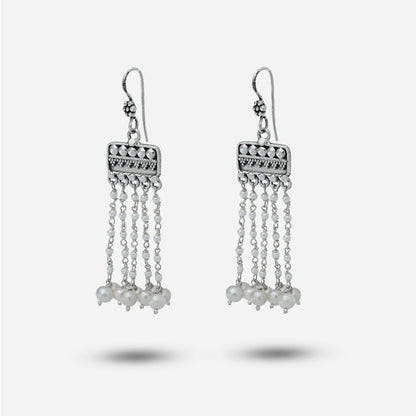 Silver chandelier earrings with pearl-like beads on a light gray background