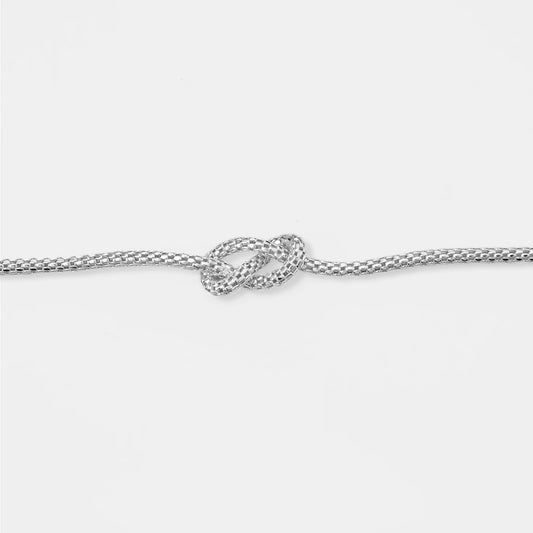 Silver bracelet with a knot design on a white background