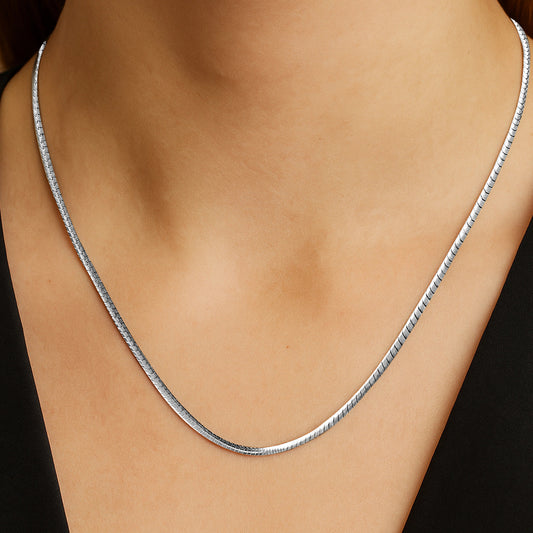 Silver necklace on a person's neck against a black background