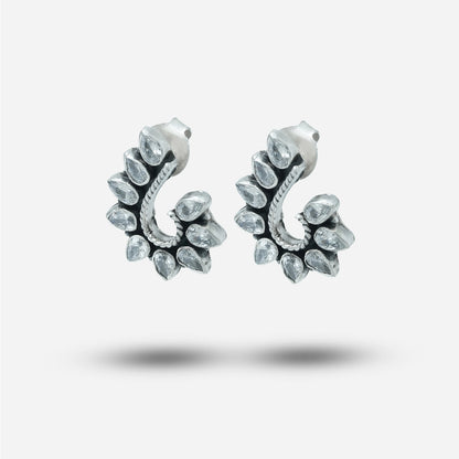 Pair of silver traditional earrings with clear gemstones on a light gray background